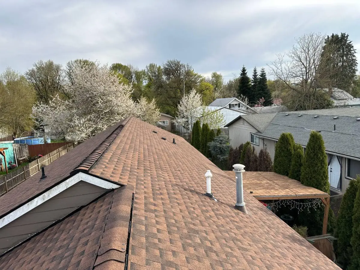 Finished tan shingle roof in a quiet neighborhood with spring blossoms