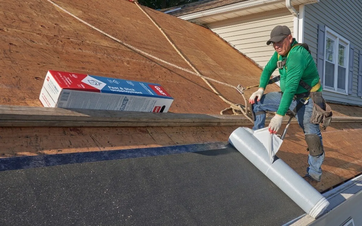 Roofer peeling back GAF WeatherWatch ice and water membrane at the eave
