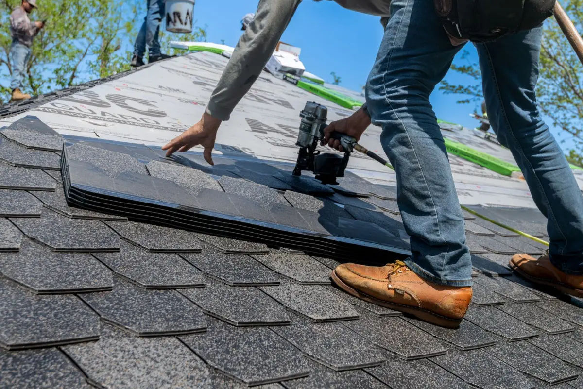 Roofer nailing a course of asphalt shingles into place